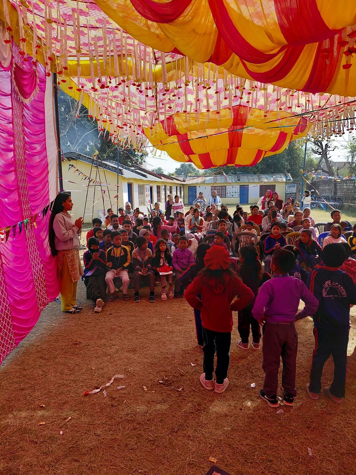 The school ground decorated with a bright canopy and flags, full of students and families