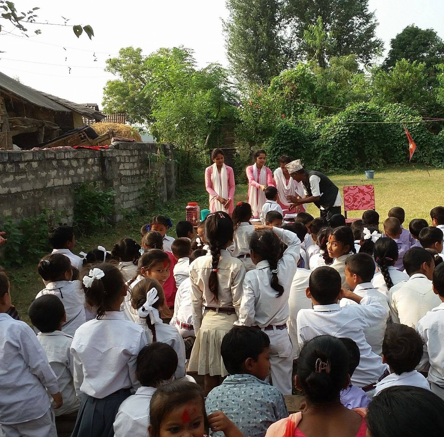 Students in white uniforms gathered for morning assembly under large trees