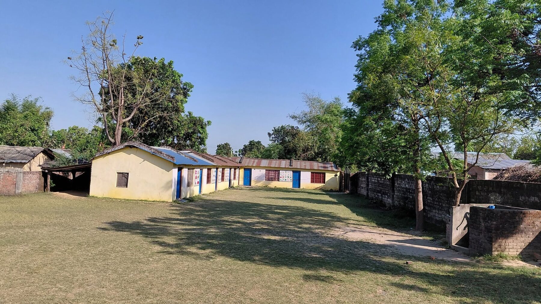 The school buildings and green playground seen from across the ground