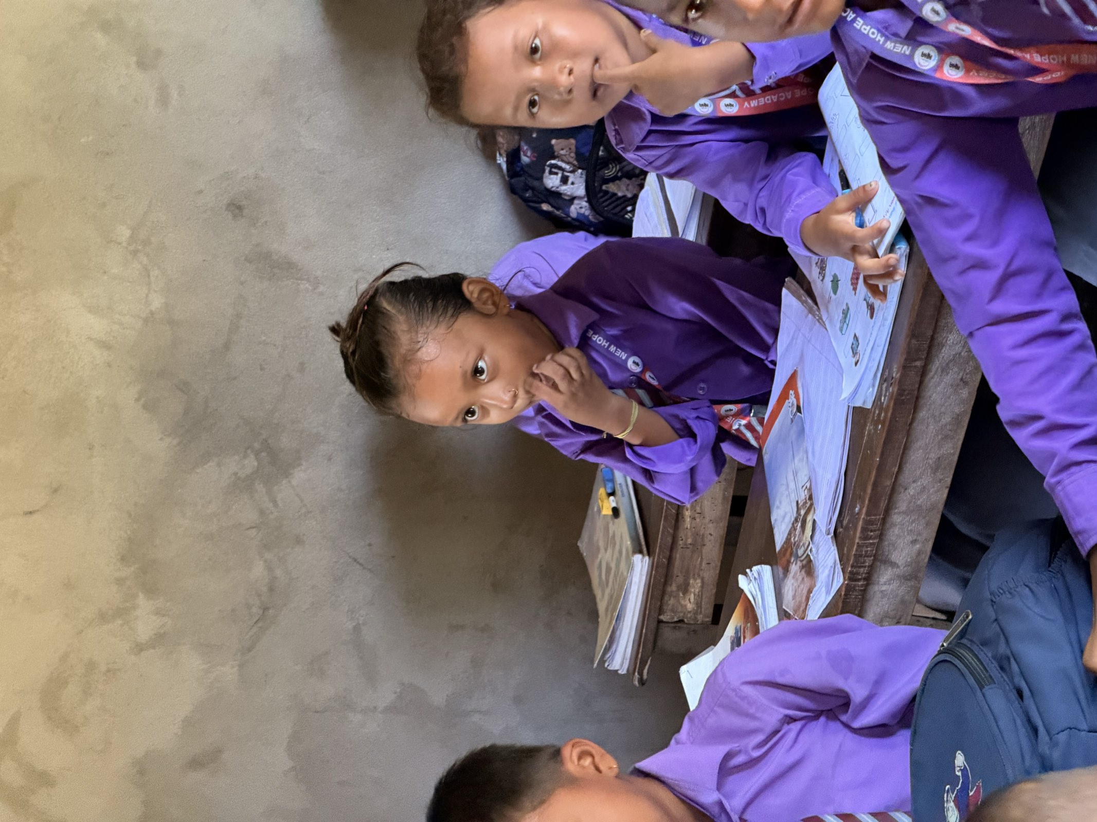 Students at their desks mid-lesson, one girl looking up deep in thought