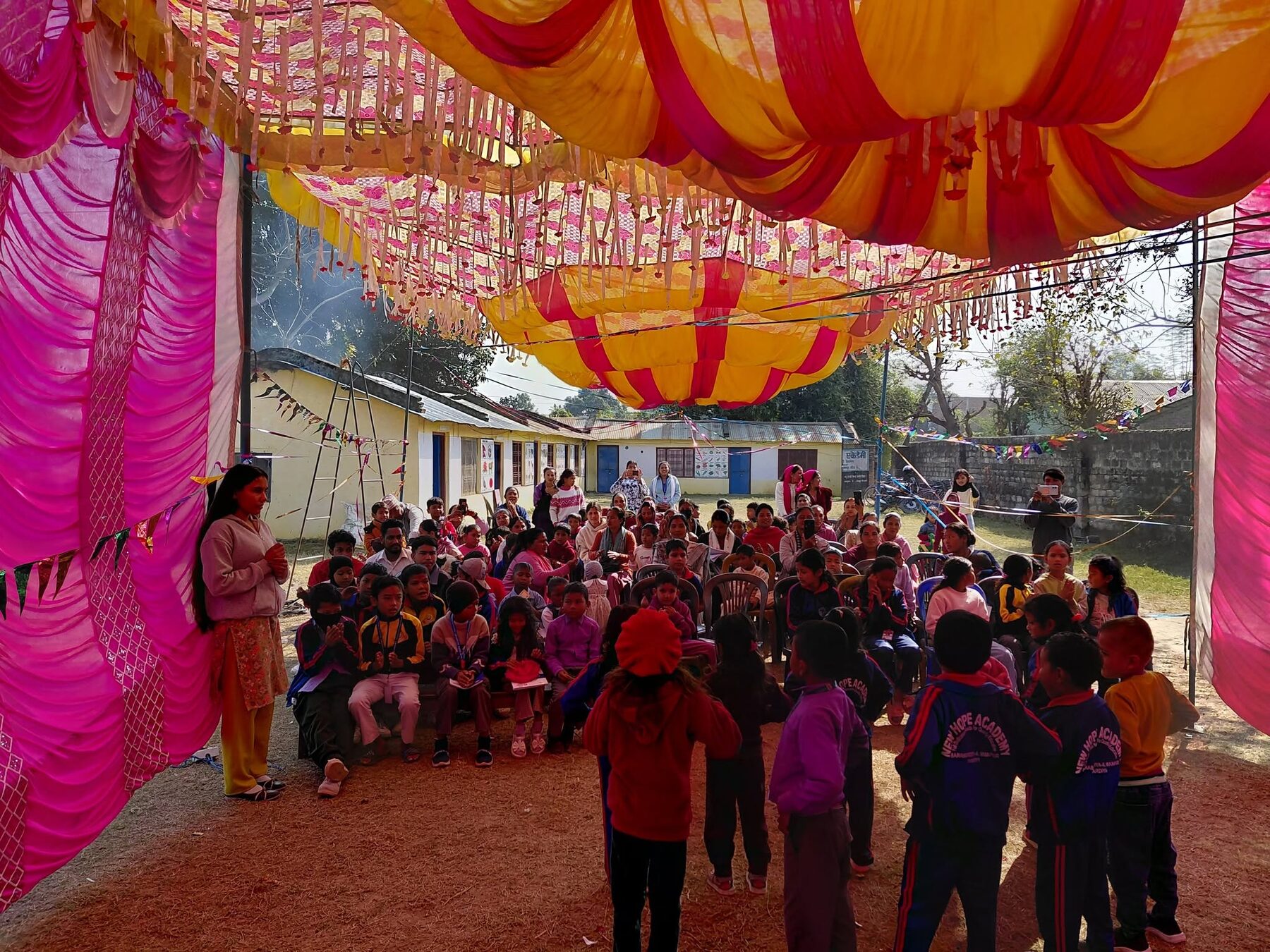 The whole school celebrating on the ground, Nepali flag waving