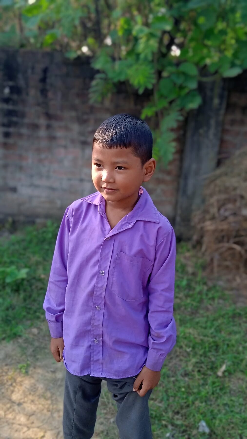 A young New Hope student in a purple shirt, standing proudly by a tree
