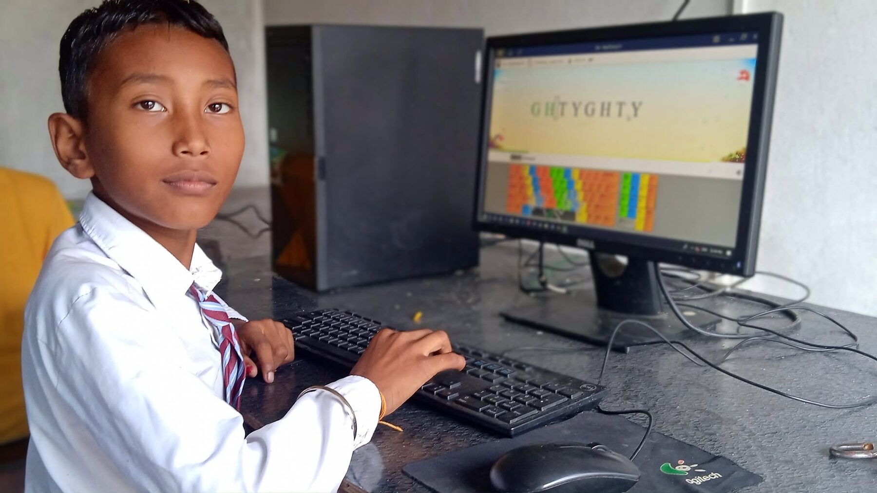 A student in uniform concentrating at a desktop computer
