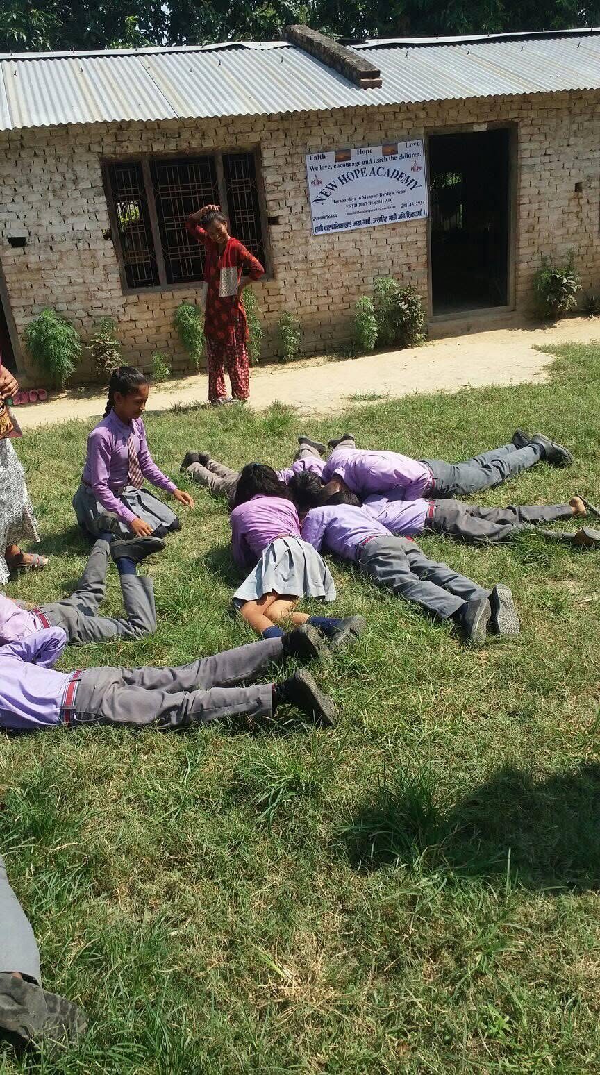 Students lying on the grass together forming letters with their bodies