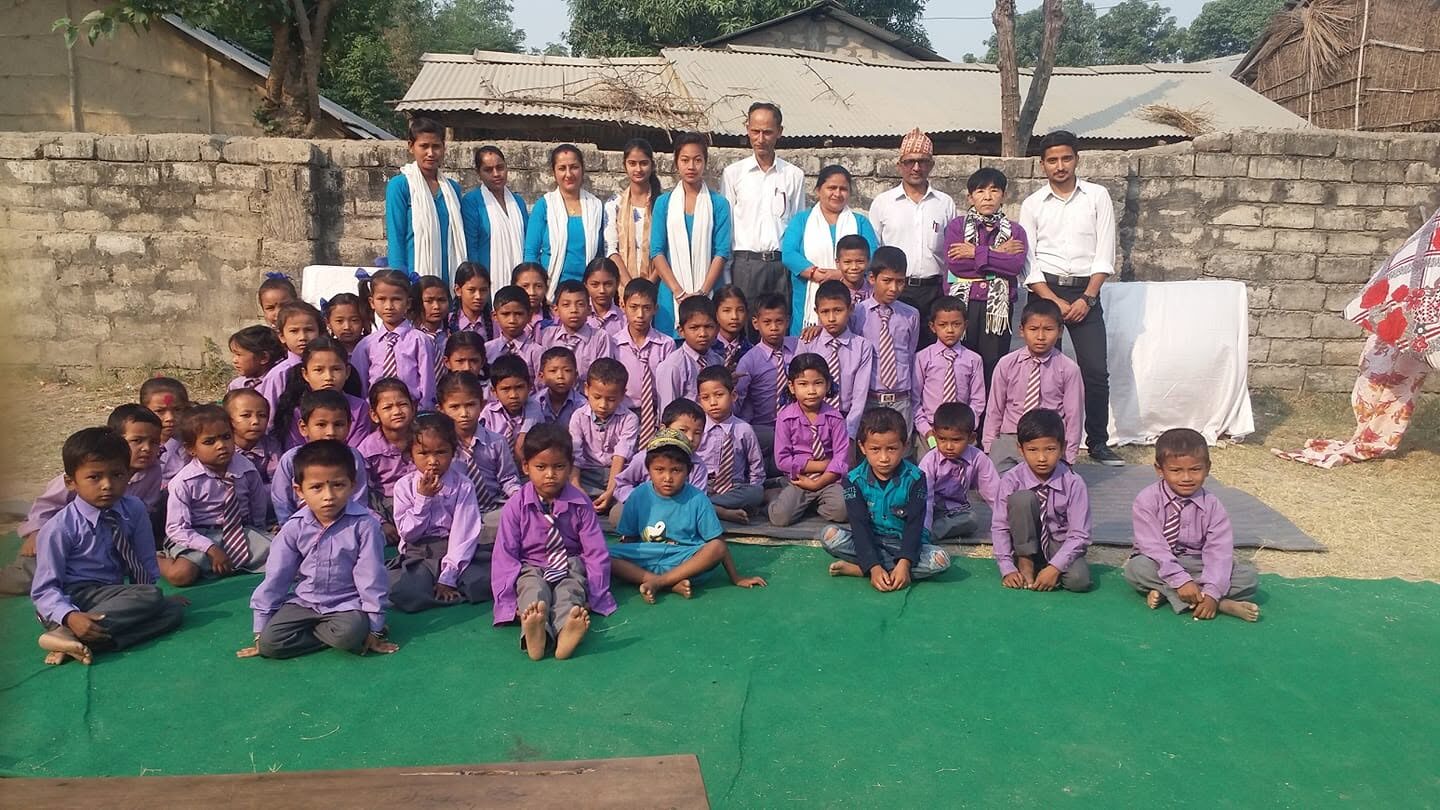 The whole school, students in purple and teachers in blue and white, posing together on the green mat